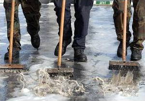 Sailors scrubbing the deck of a boat with brushes, soap, and water